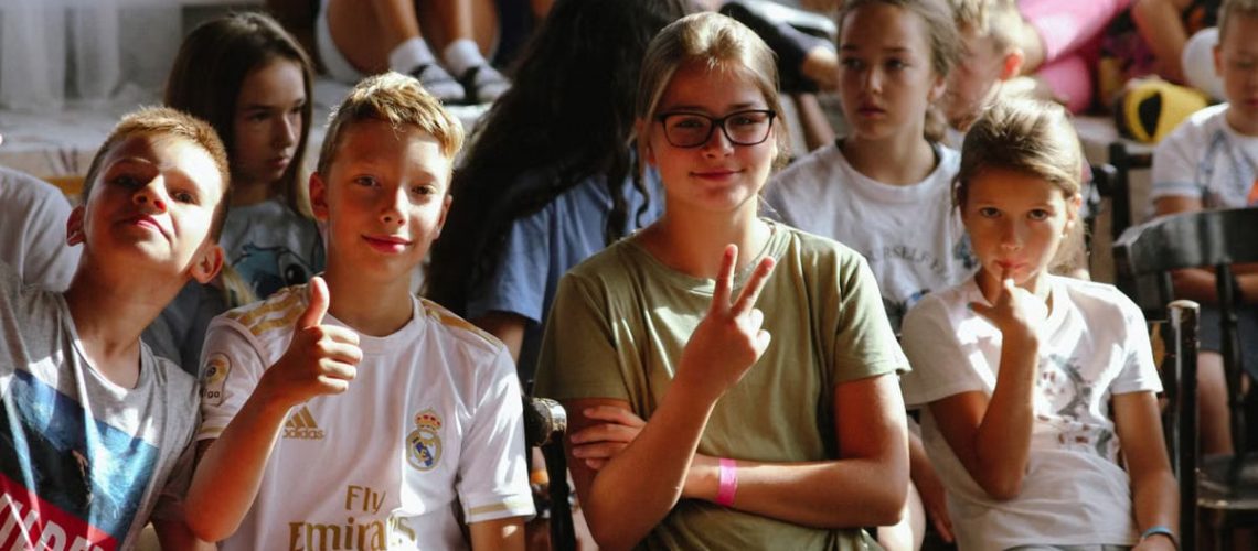 Cheerful group of children sitting together at an indoor event, showcasing friendships and diversity.